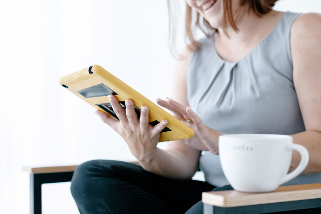 sitting on chair with coffee and reviewing tablet