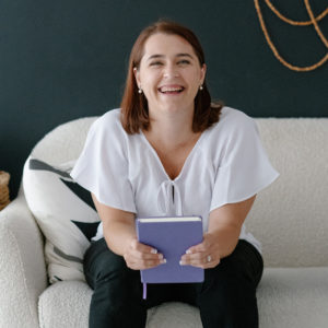Melanie Ziltener sitting on a sofa being a content strategistwith her notebook