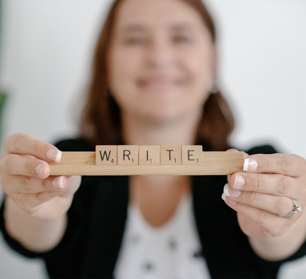 woman holding scrabble tiles spelling 'write'